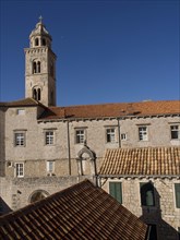 Historic church with bell tower and roof tiles under a clear blue sky, the old town of Dubrovnik