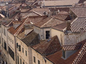 View over a collection of tiled roofs in an old town, with historic buildings and narrow streets in