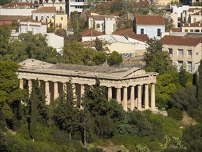 View of an ancient temple with columns in the city area, surrounded by trees, Ancient buildings