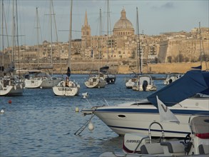 Harbour with sailing boats and view of cathedral and city walls in the background, Valetta, Malta,
