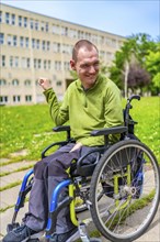 Vertical exterior portrait of a disabled man smiling sitting in the electric wheelchair in the