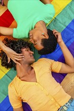 Vertical top view photo of a male latin gay couple caressing over a LGBT rainbow flag