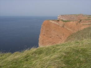 Steep orange cliffs on the coast with a view of the wide blue sea, Heligoland, Germany, Europe