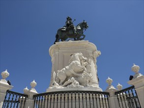 Large equestrian statue on pedestal, surrounded by balustrade, blue sky indicates sunny weather,