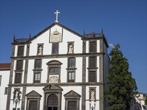 Historic church with white and brown facades, religious ornaments, under a clear blue sky, the