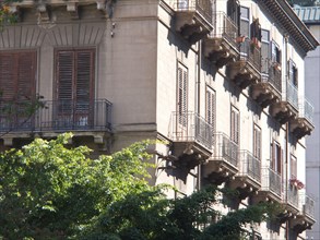 Multi-storey building with numerous balconies and shutters, partly in the shade, palermo in sicily