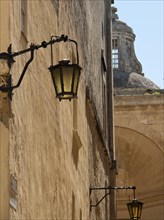Historic lantern along an old wall with arch structure and blue sky in the background, Historic
