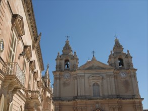 Baroque church with two bell towers in the bright blue sky, the town of mdina on the island of