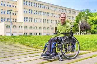 Full length portrait of a caucasian young man with cerebral palsy in wheelchair in the university
