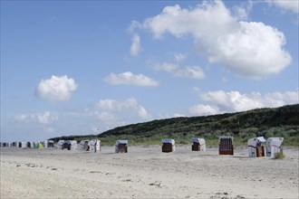 Row of beach chairs along the deserted beach, with sand and dunes in the background, Spiekeroog,