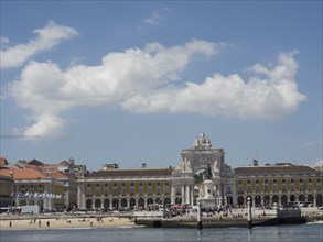 Spacious square with historical buildings in the background, some people and blue sky with white