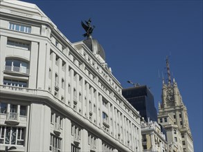 White buildings with towers and a statue on the roof, blue sky in the background, Madrid, Spain,