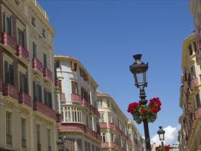 Colourful old town houses with floral decorations and street lamps on a sunny day, Malaga on the