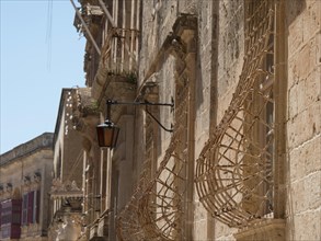 Historic street with stone facades and lanterns in a sunny town, the town of mdina on the island of