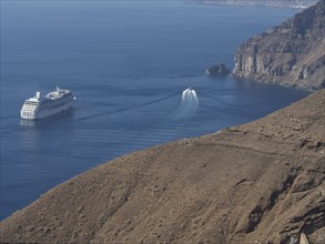 A cruise ship and a smaller boat sail along a rocky coast in the ocean, The volcanic island of