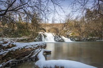 Beautiful landscape in winter with ice and snow. Waterfall of the river Elz near the castle