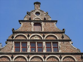 Historic house with elaborate brick facade and windows under a blue sky, medieval facades with