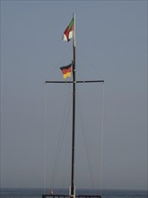 Two flags on a high mast over calm sea, wide sky, Heligoland, Germany, Europe
