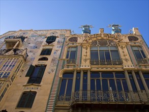 Decorative building with artistic mosaic work on the facade and several balconies under a clear