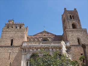 Historic cathedral with two towers and decorated facade, statue in the foreground, palermo in
