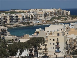 View of a coastal town with waterfront buildings and the blue sea in the background, the island of