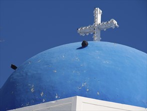Blue dome with a white cross on a mediterranean church building, The volcanic island of Santorini