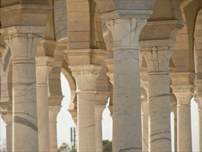 Several beige columns of an ancient arcade with shadow plays in the light, Tunis in Africa with
