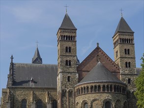 A historic church with several sandstone towers under a blue sky, Gothic architecture, Maastricht,
