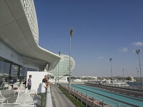 Two men stand on a terrace of a modern building under a blue sky, Abu Dhabi, Arab Emirates