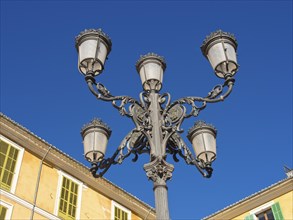 Decorative street lamp in front of historic buildings and blue sky, palma de Majorca with its