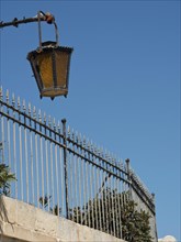 Street lamp over a metal fence with blue sky in the background, the town of mdina on the island of