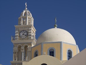 A tall bell tower and a domed church rise up against a bright blue sky, The volcanic island of