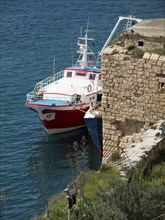 Red and white fishing boat and stone structure at the harbour, Valetta, Malta, Europe