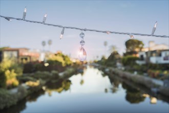 A string of lights and a quartz crystal are hanging on a string above a canal at Venice Beach,