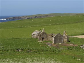 An old stone building stands alone in a green field under a clear blue sky, Green meadows by the