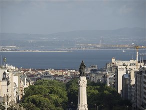 View of a monument in a city with sea and hilly landscape in the background, Lisbon, Portugal,