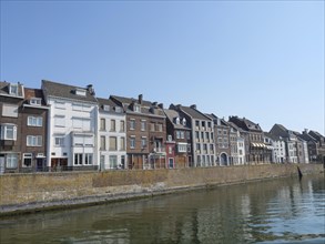 A row of old houses along a canal on a sunny day with a quiet atmosphere, Maastricht, Netherlands