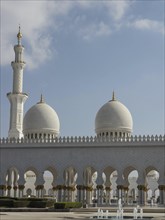 A magnificent mosque with minaret and golden domes against the blue sky, Abu Dhabi, Arab Emirates