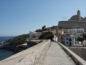 Historic city wall and buildings overlooking the sea under a clear blue sky, ibiza, Spain, Europe