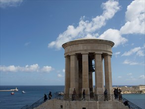Round building with columns as a viewing platform under a blue sky with some people, Valetta,
