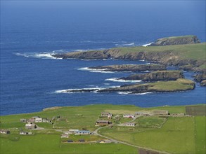 Coastal landscape with green fields, scattered houses and rocky cliffs by the deep blue sea, Green