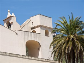 Mediterranean church with white walls and a palm tree under a clear blue sky in summer, palermo in