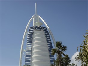Close-up of the Burj Al Arab, a modern architectural icon, with some palm trees in the foreground