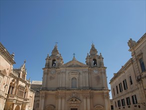 Historic buildings with a large church in the centre and two bell towers, the town of mdina on the
