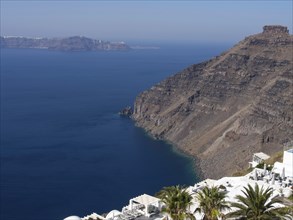 A calm coastline with steep cliffs and clear sea under a cloudless sky, The volcanic island of