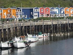 Colourful houses at the harbour with boats in the water and a clear blue sky, Heligoland, Germany,