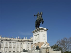 Equestrian statue on a pedestal in front of a historic building and blue sky, Madrid, Spain, Europe