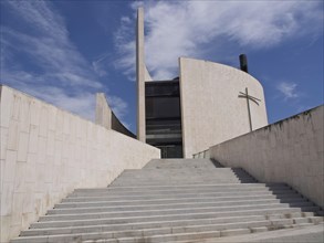 Wide staircase leads to a modern church with a cross under a blue sky, Barcelona, Spain, Europe
