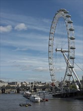 The London Eye next to the Thames under a slightly cloudy sky, London, England, United Kingdom,