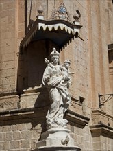 Close-up of a baroque statue on a stone house wall under a blue sky, Historic buildings with